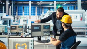 Solar panel manufacturing plant manager showing engineer on PC how to develop prototypes for new solar energy systems. Team leader telling technician about new photovoltaics materials, camera A